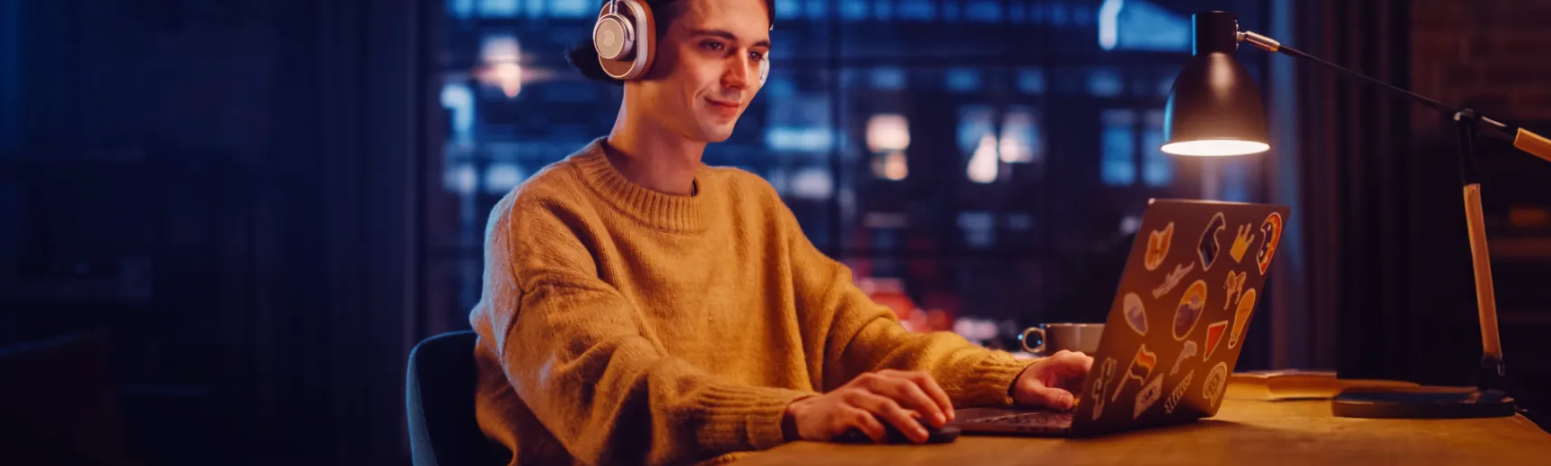 A man sitting in front of a laptop wearing headphones.