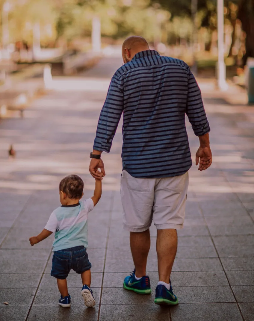 A father holding the hand of his small child.