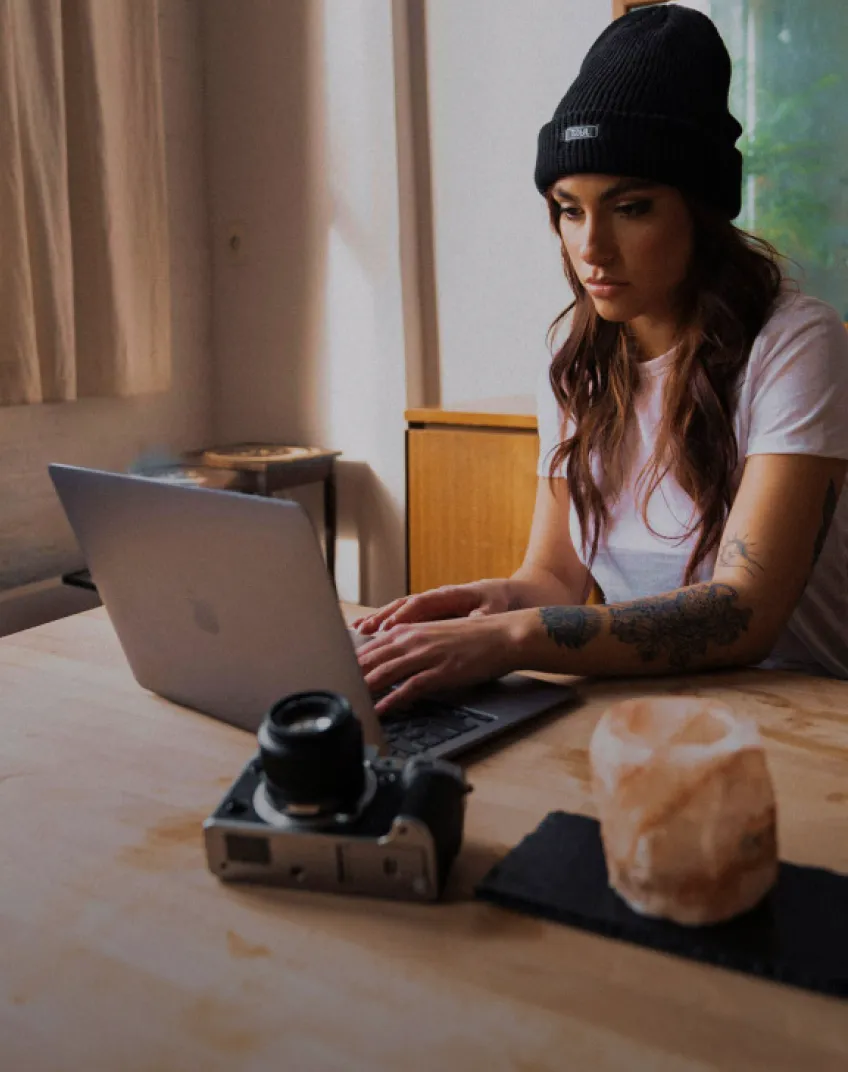 A woman sitting at a table using a laptop computer.